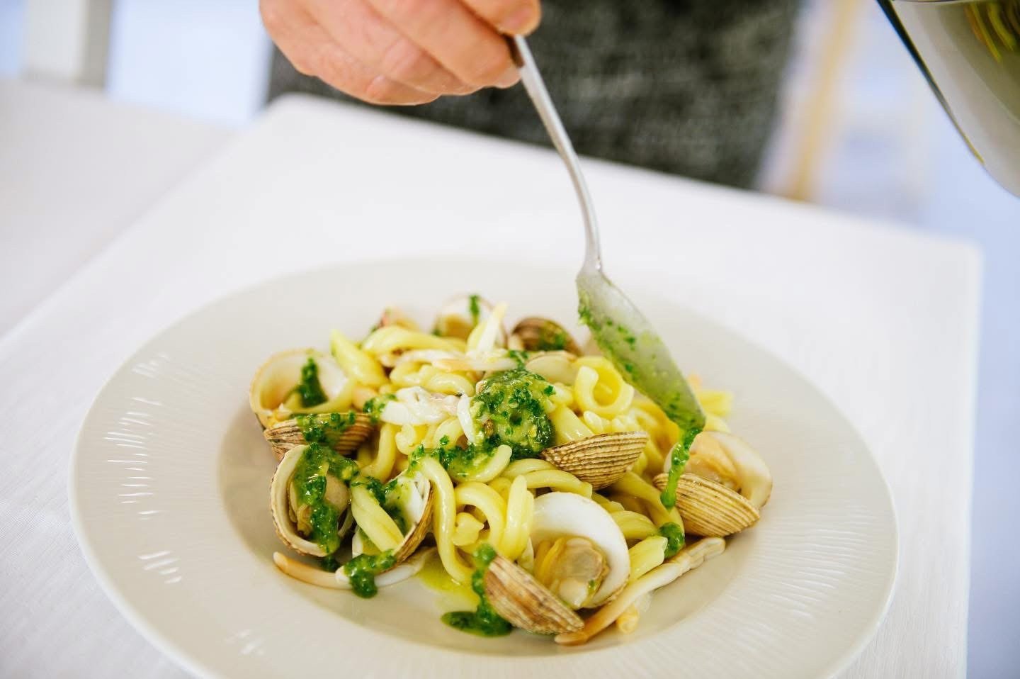 Piatto di pasta corta con frutti di mare e verdure, forchetta in mano, luce naturale, Hostaria del Vicoletto