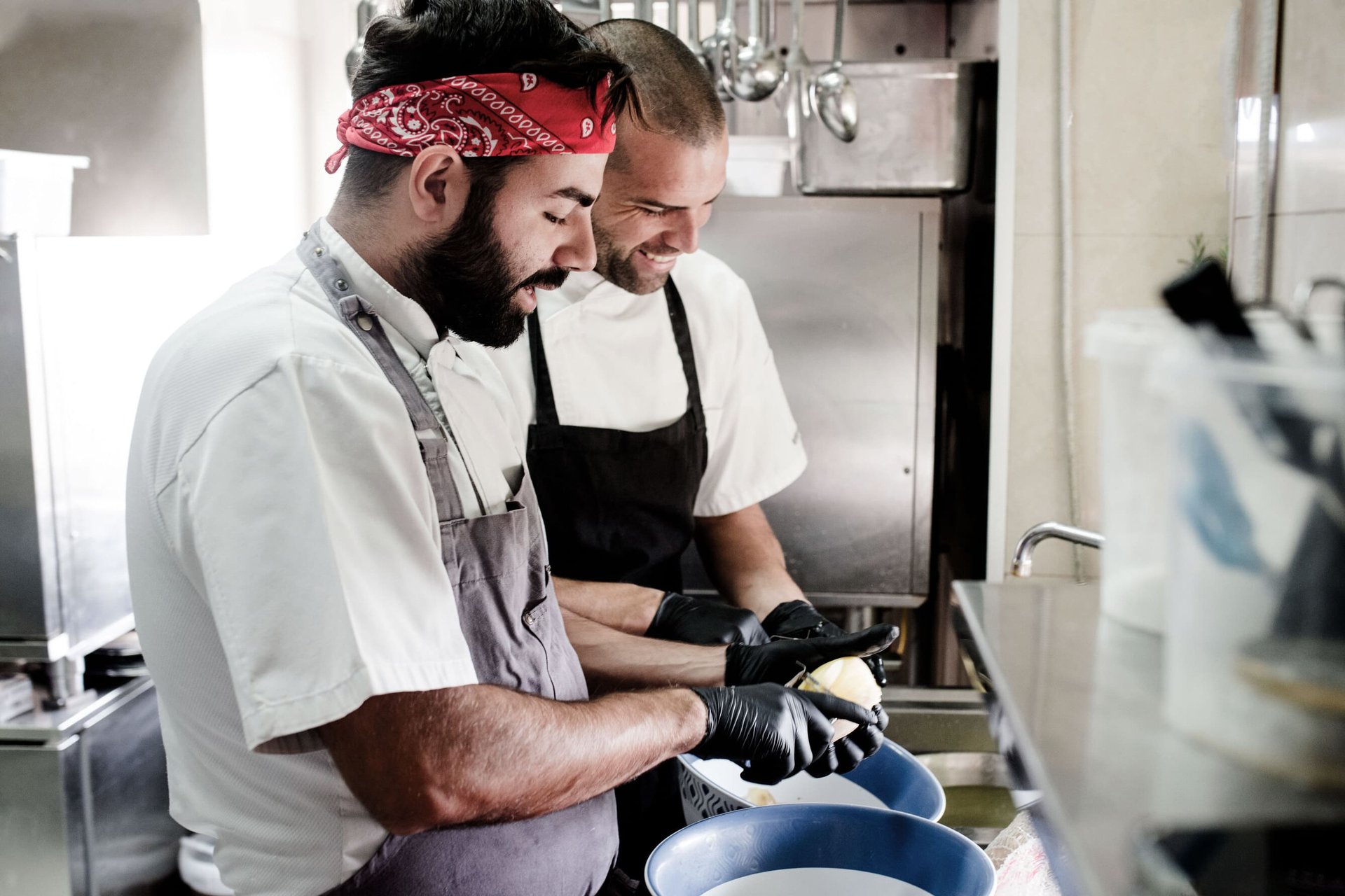Due cuochi sorridenti al lavoro in cucina (bandana rossa, guanti neri), Il Granchio