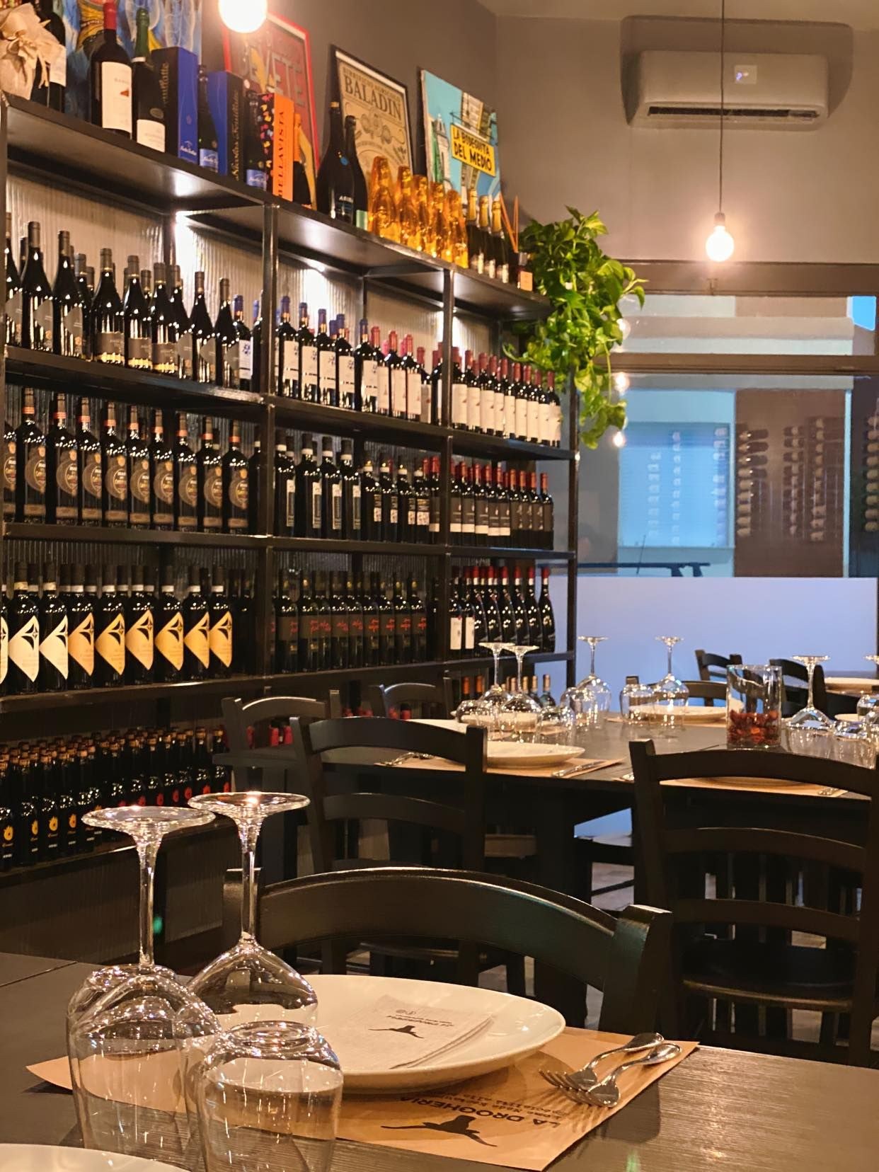 La parete delle bottiglie di vino accanto ai tavoli, La Drogheria Restaurant