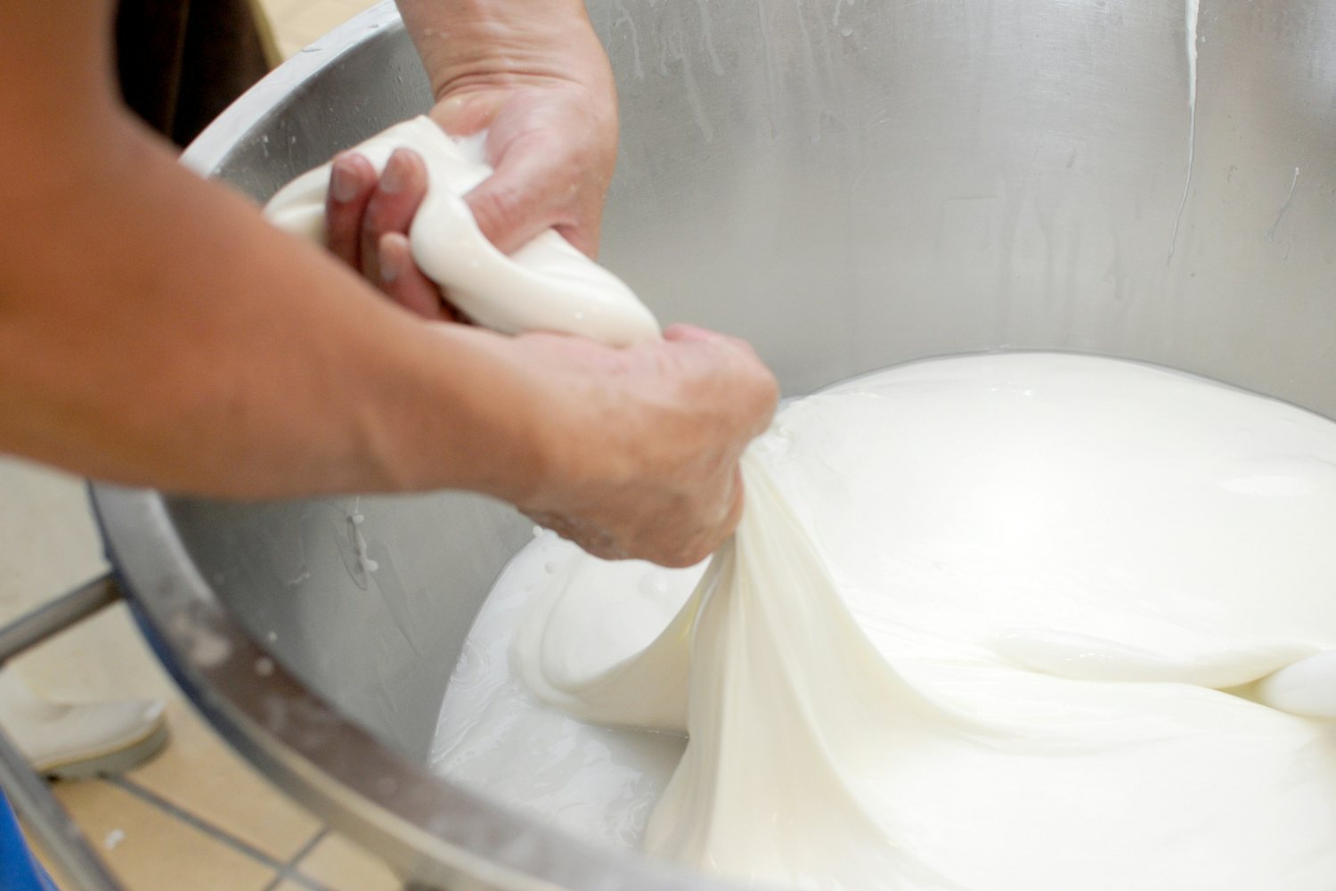 Mani che lavorano la pasta filata nella caldaia