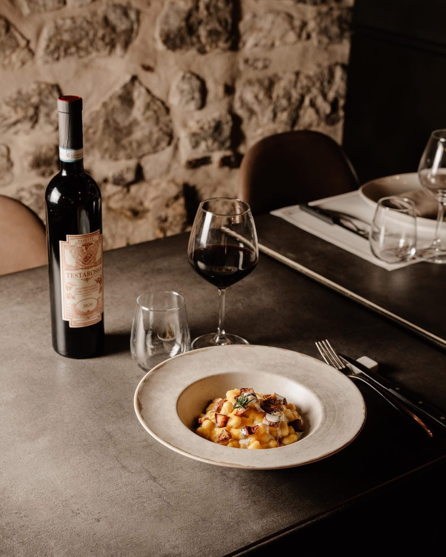 Tavolo apparecchiato con bottiglia di rosso, calice e piatto di pasta, parete di pietra (stesso file di B-lepini-appia/foto/P7-terracina-campo-dei-fiori-tavola.jpg), Osteria Campo de Fiori
