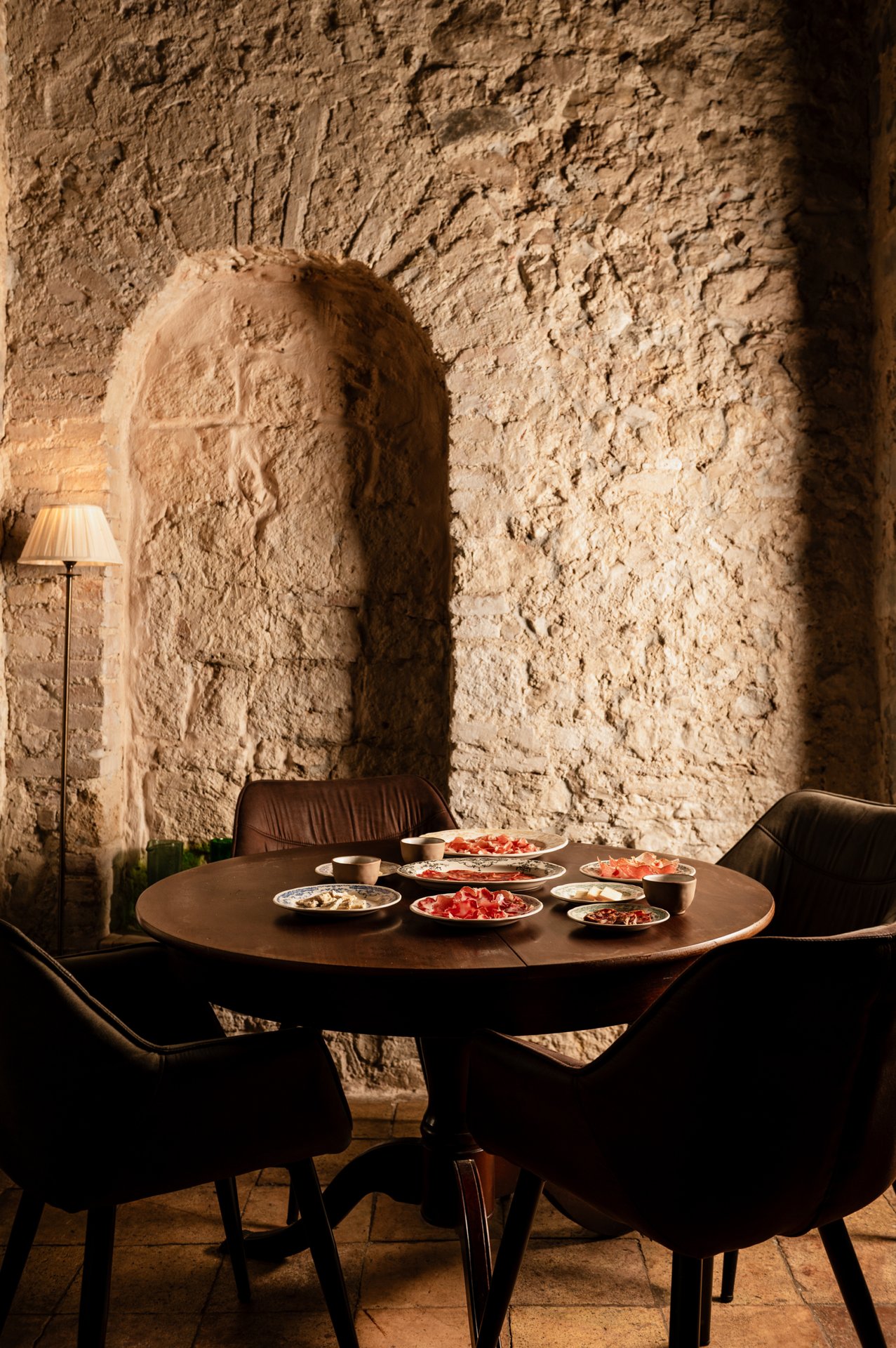 Tavolo rotondo con 7-8 piattini di salumi e antipasti in sala a volta di pietra, Ristorante Indigo